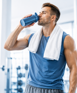 Athlete drinking a recovery shake after an intense workout in a modern gym